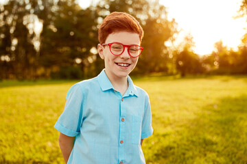 Smart redhead boy in glasses in park