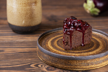 Piece of vegan chocolate eggplant brownie with cherries on a wooden table. Sugar, gluten, lactose free.