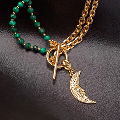 Female golden moon shaped pendant with golden chain and green malachite - obrazy, fototapety, plakaty