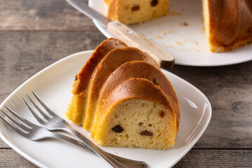 Traditional bundt cake piece with raisins on wooden table	