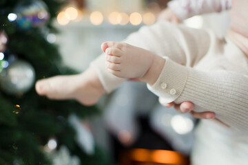 Fototapeta premium Baby feet near Christmas tree lights