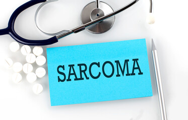 Text SARCOMA on a table with a stethoscope,pills and pen, medical concept.