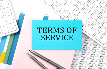 Obraz premium TERMS OF SERVICE text on blue sticker on chart with calculator and keyboard,Business concept