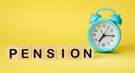 The word PENSION on wooden cubes. There is an alarm clock on a yellow background. Time is money. Finance concept.