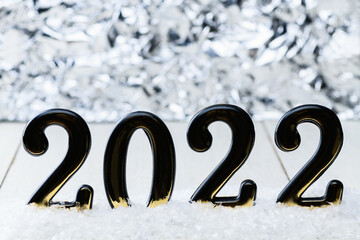Black numbers 2022 on white background with snow. New year backdrop with 2022 year
