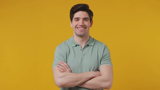 Handsome fun stylish young man 20s years old wear green polo shirt look camera asides charming toothy smile isolated on plaine yellow color background studio portrait People emotions lifestyle concept