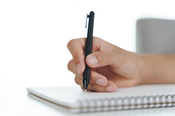 Close up of man hand writing down on the notepad, notebook using ballpoint pen on the table.