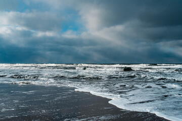 Winter landscape with frozen sea and icy beach. Storm and snow weather. Dramatic seascape.