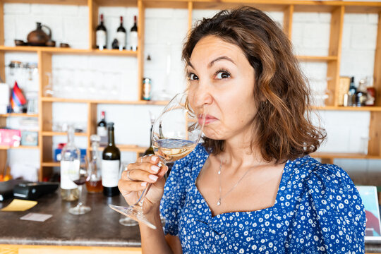 Woman sniffs and tasting bad wine. The concept of loss of sense of smell and long covid