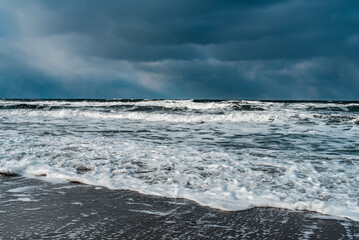 Winter landscape with frozen sea and icy beach. Storm and snow weather. Dramatic seascape.