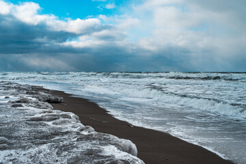 Winter landscape with frozen sea and icy beach. Storm and snow weather. Dramatic seascape.
