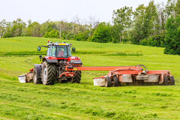 Obraz premium A tractor with two rotary mowers mows the grass. Mowers in front and behind the tractor