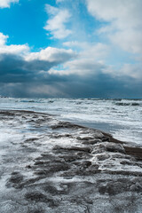 Winter landscape with frozen sea and icy beach. Storm and snow weather. Dramatic seascape.