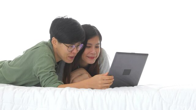 Happy Asian lesbian couple leisure activity concept, elder glasses female talking younger woman pointing laptop online shopping on bed