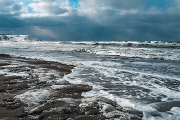 Obraz premium Winter landscape with frozen sea and icy beach. Storm and snow weather. Dramatic seascape.