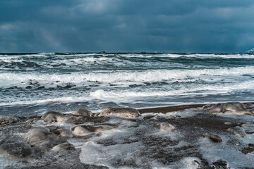 Winter landscape with frozen sea and icy beach. Storm and snow weather. Dramatic seascape.