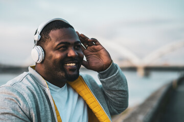 Modern black man with headphones  enjoys listening music outdoor.