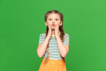 The little girl grabbed her cheeks and made a sponge tube. Child on a green isolated background. Copy space.