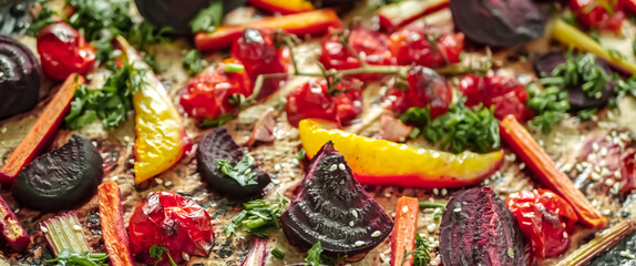 Fototapeta premium Roasted vegetables beets, tomatoes, peppers, carrots, close up. Vegan recipe baked vegetables background. Healthy food concept, Baked vegetables in the oven close-up