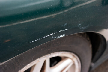Car wheel arch paint damage. Small scratch white pant transfer from parking space poll. Close up shot, no peop