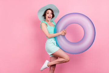Portrait of attractive cheerful ecstatic girl holding rubber ring having fun beach isolated over pink pastel color background