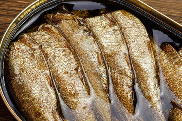 Food background, canned fish in a tin can, sprats smoked in oil seafood close-up top view