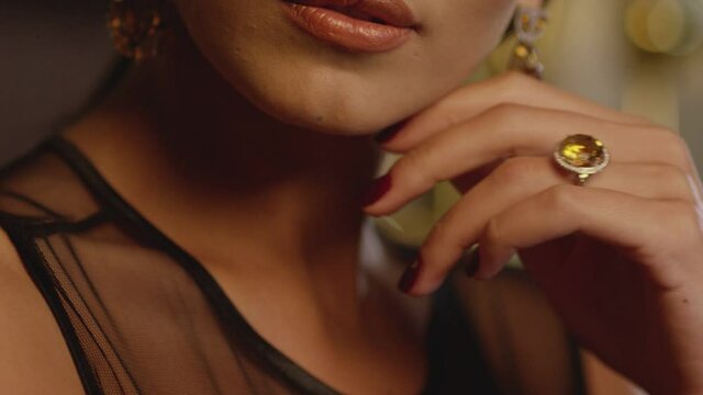 Beautiful brunette woman wearing  luxury expensive jewelry with yellow shining diamonds . Girl's hand slowly touching and caressing her beautiful white  neck and showing earring and ring . Closeup
