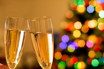 Blurred christmas tree and two glasses filled with sparkling wine champagne. New year concept