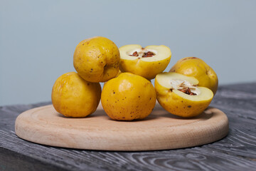 Quince fruits on a cutting board. The yellow fruit is cut, the seeds are visible. On black pine boards. Close-up shot.