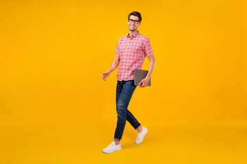 Fototapeta na wymiar Full body profile side photo of young man happy positive smile go walk hold laptop meeting isolated over yellow color background