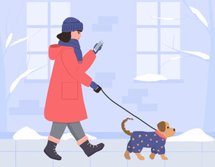 A girl in a warm coat, hat and gloves walks with a dog down the winter street and looks at the phone. A small dog in a blue jumpsuit. Vector illustration in flat style