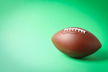 American football ball on mint background, space for text