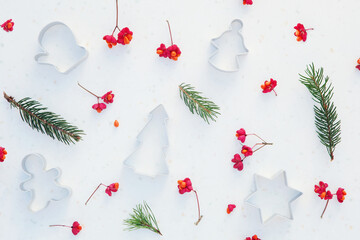 Christmas composition. Pine green branches with red berries, cookie cutters on white background. Christmas background, top view, horizontal image.