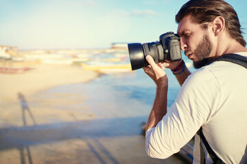Fototapeta na wymiar Photography and travel. Young man taking photo with his camera on the sea beach.