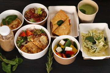 Healthy restaurant food delivery, business lunch and diet plan, fresh daily meals. Daily vegetarian food in eco boxes with copy space in dark wood. 