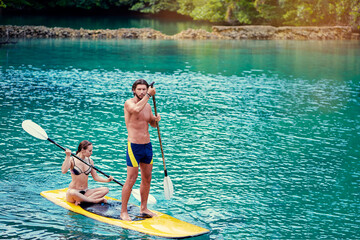 Summer holidays vacation travel. SUP Stand up paddle board. Young woman and man sailing together on...