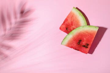 Delicious ripe watermelon and tropical leaf shadow on light pink background, flat lay. Space for text