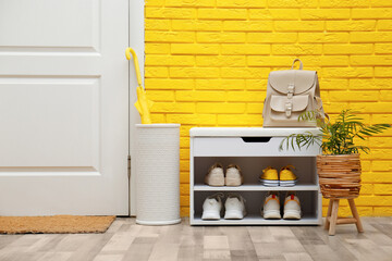 Shelving unit with shoes near yellow brick wall in hallway