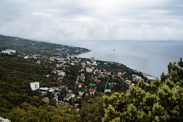 Panoramic view of the city by the sea from above. Seaside coast with villas. Summer day by the sea. Small houses