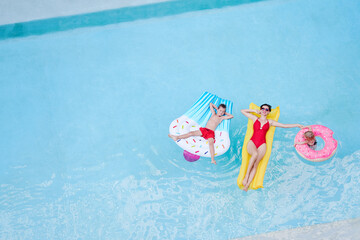 Vacation with a family. Top view of happy young mother and her kids on the air mattreses having fun...