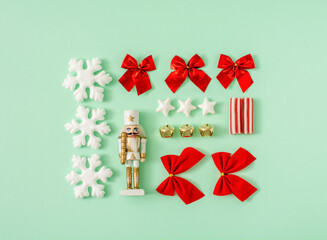 Christmas composition on a mint green background. Christmas, winter, new year concept. Nutcracker, bow, ribbon, stars and balls. Card and advent minimal creative concept.