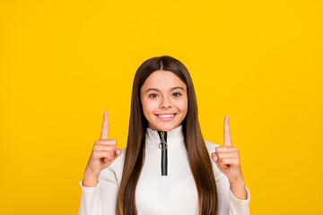 Photo of charming pretty student girl wear white zip shirt smiling pointing up empty space isolated yellow color background