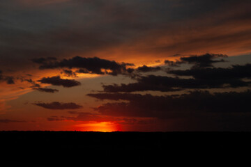 The red sun has disappeared below the horizon and fantastic clouds cover the entire sky. Sunset.