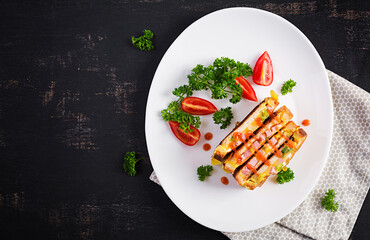 Roasted sandwich cheese,hm, peppers and scrambled eggs on white plate. Dark background. Top view, flat lay