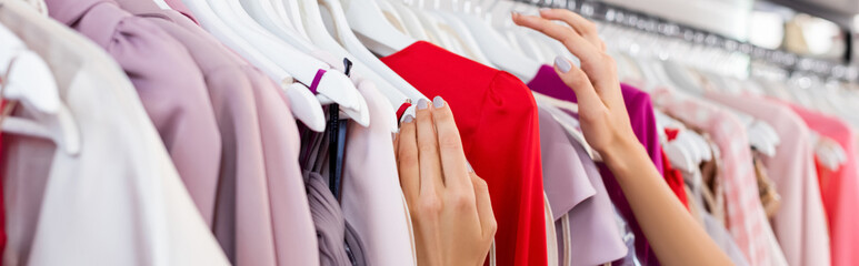 partial view of woman choosing clothing in boutique, banner - obrazy, fototapety, plakaty