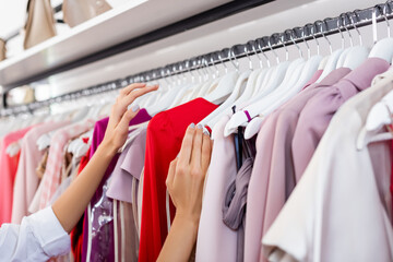 partial view of woman choosing clothing in boutique