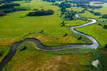 Aerial view of the green fields and small curved river in a sunny day.