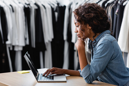 Side View Of Curly African American Woman Using Laptop On Sales Counter Desk