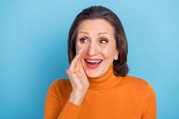 Portrait of positive pretty lady arm palm near mouth look interested empty space say tell isolated on blue color background