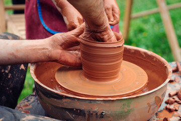 Potters and child hands. Family working on pottery wheel. Dad and child making ceramic pot together.